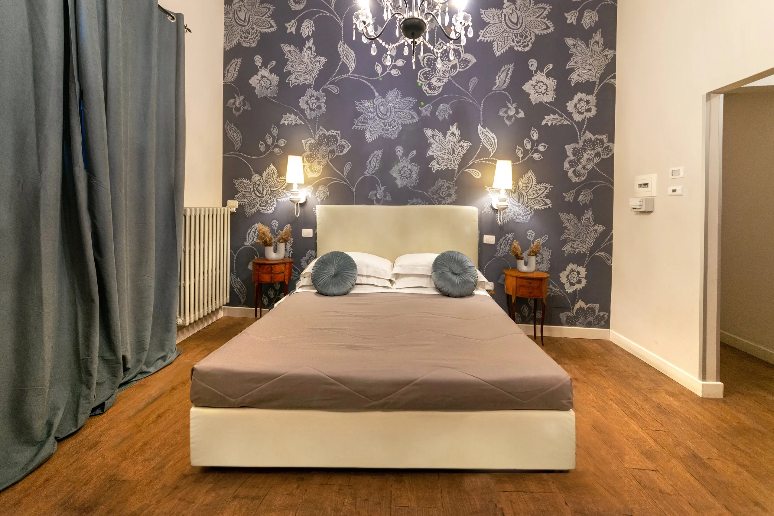 Il letto della Junior Suite visto di fronte, tra i comodini in legno e le applique