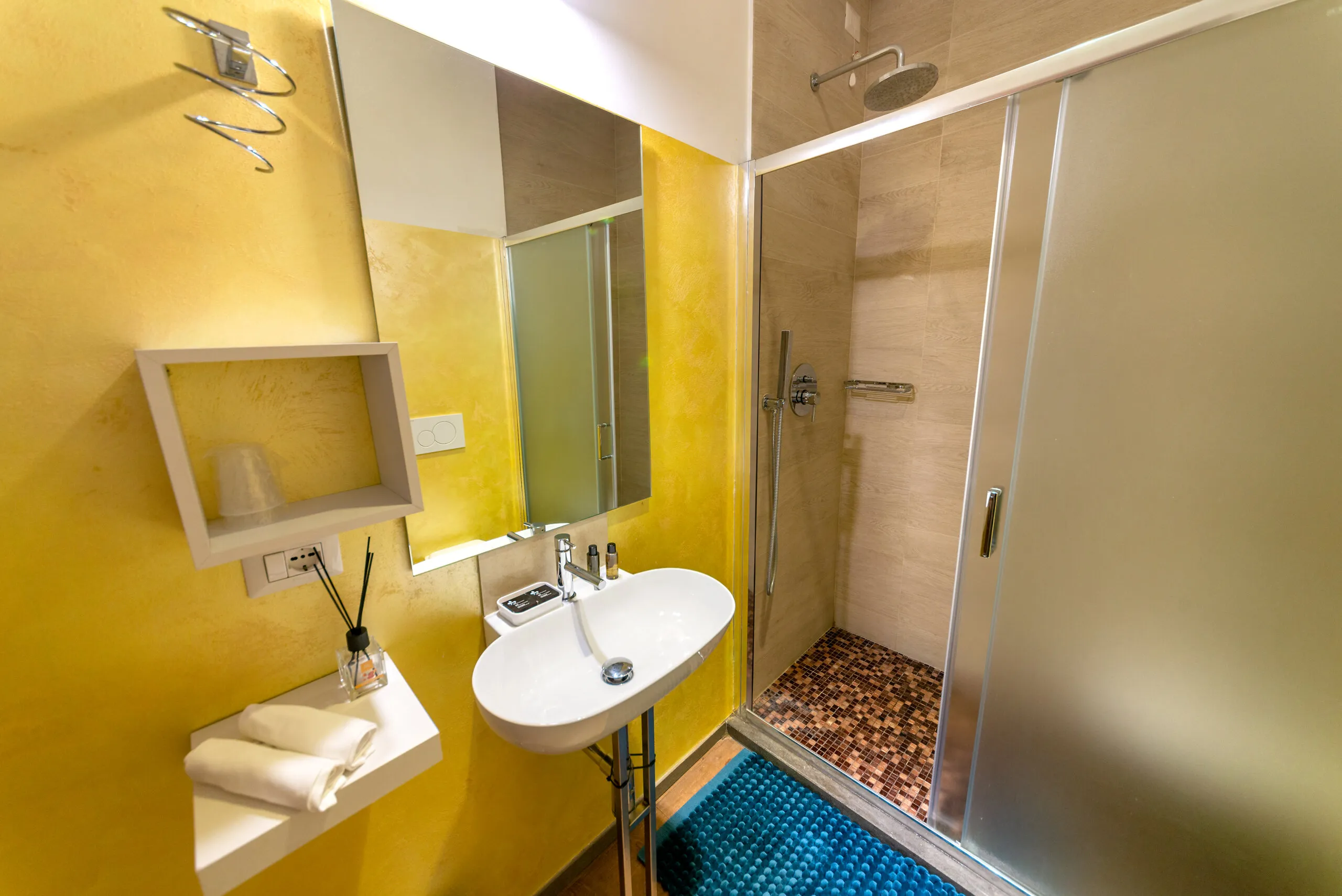 Il bagno della Standard 01, con pareti gialle e doccia rivestita a mosaico