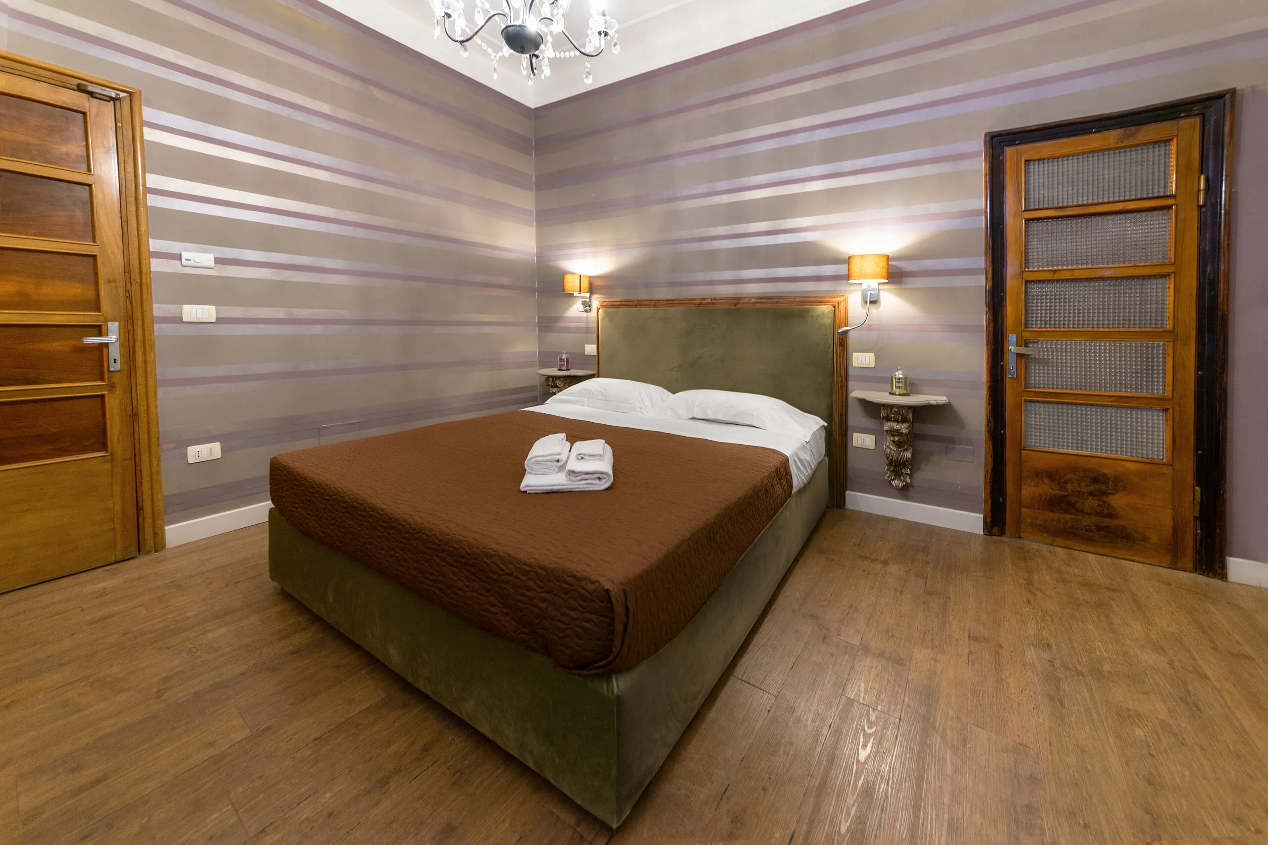 Il letto della Superior con copriletto marrone, tra le porte in legno della camera